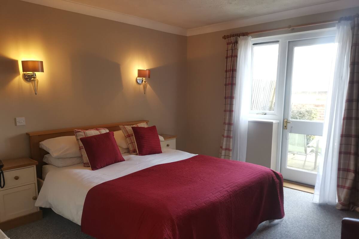 A bedroom with a bed, two bedside lamps, a nightstand, and a window with curtains.