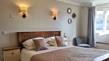A neatly made bed with a wooden headboard, a bedside table with a lamp, and wall-mounted sconces.