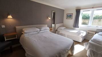 Habitación de hotel con dos camas, una mesita de noche, una lámpara de pared y cortinas en la ventana.
