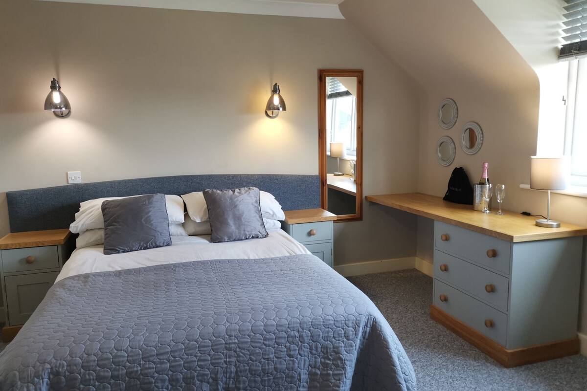 A bedroom with a bed, bedside tables, a dresser, a mirror, and wall decor.