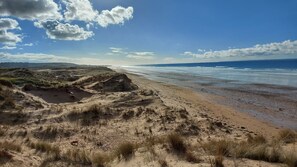 Une plage avec des dunes et un ciel dégagé.