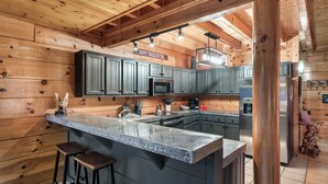 Een moderne keuken met houten wanden, een granieten eiland en roestvrijstalen apparatuur.