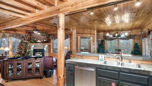 Een rustiek houten interieur met een keuken, inclusief een groot eiland, inbouwmeubels en een open haard.