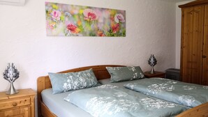 Ein Schlafzimmer mit einem hölzernen Bett, Bettwäsche mit Blumenmuster, einem Nachttisch mit Lampe und einem Holzschrank.