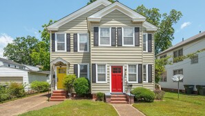 A two-story house with a red front door, a yellow door, and a satellite dish.