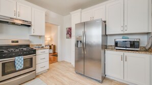 A modern kitchen with white cabinets, stainless steel appliances, and a granite countertop.