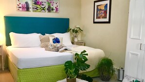 A neatly arranged bedroom with a bed, bedside plants, and artwork on the walls. - One minute's walk to Freights Bay (Freights Bay)