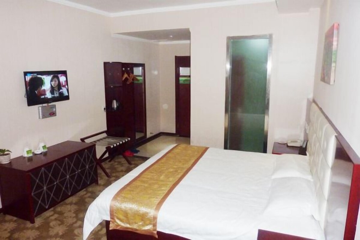 Una camera d'albergo con un letto, una televisione, una scrivania e un armadio.