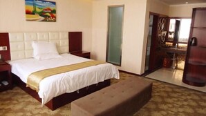 A hotel room with a large bed, a bench, a painting on the wall, and a view of the kitchen through an open door. - Greentree Inn Henan Shangqiu Yongcheng Ouya Road Business Hotel (Shangqiu)