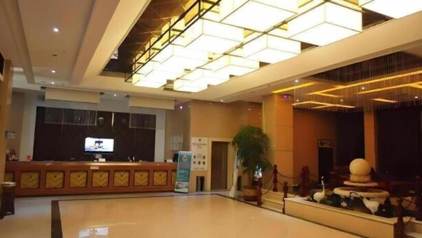 A spacious lobby with a reception desk, a large flat-screen TV, and a decorative sculpture. - Greentree Inn Henan Shangqiu Yongcheng Ouya Road Business Hotel (Shangqiu)