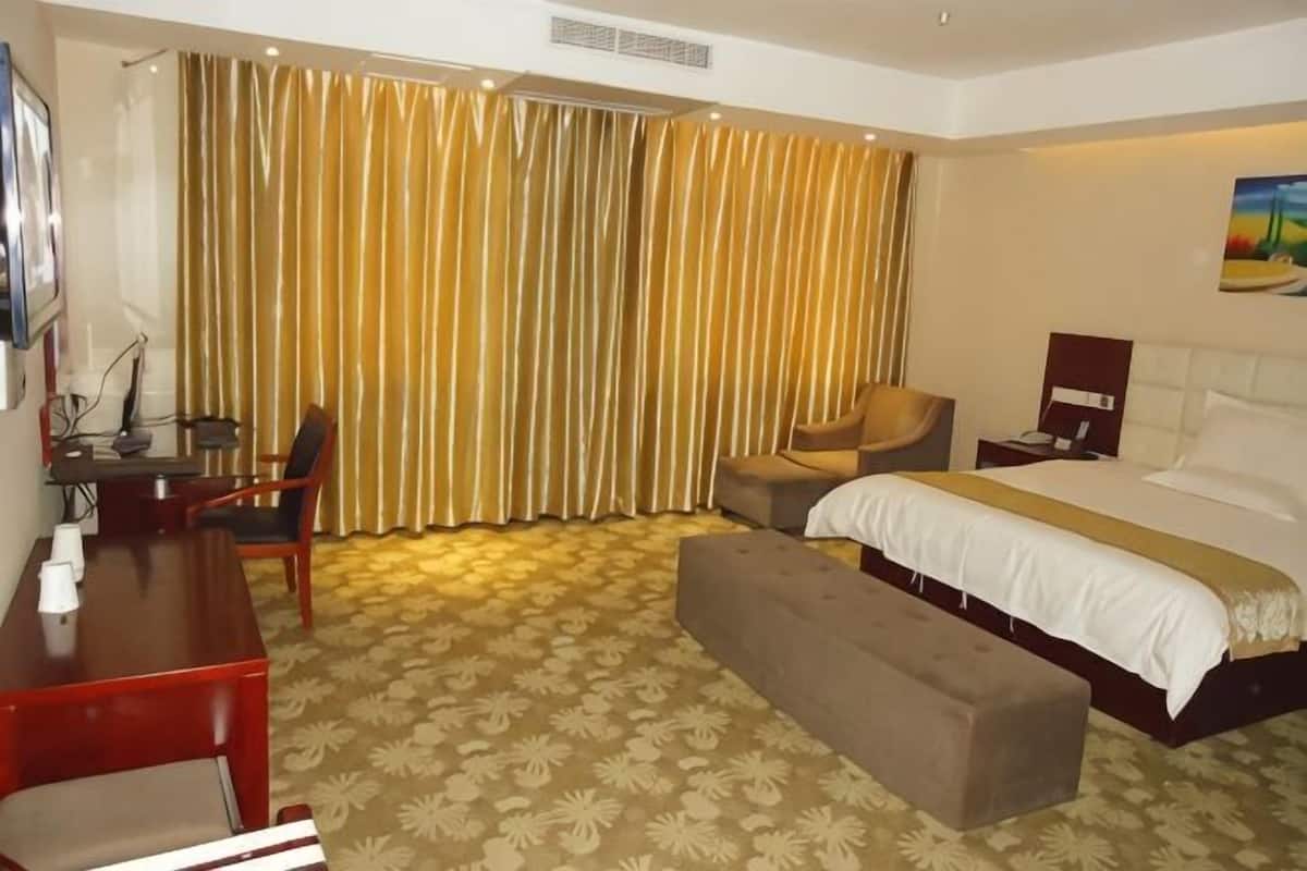 Ein Hotelzimmer mit Bett, Schreibtisch, Stuhl und einer Bank.
