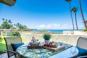 Enjoy a serene ocean view from this outdoor dining area, featuring a round table and comfortable seating.