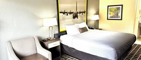 A hotel room with a bed, two bedside tables with lamps, a chair, and a large mirror on the wall.