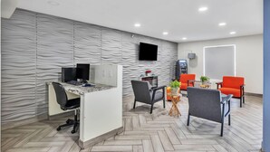 A modern office space with a curved wall, a desk with a computer, two chairs, a small table with a plant, and a whiteboard. - Super 8 by Wyndham Morganton (Morganton)
