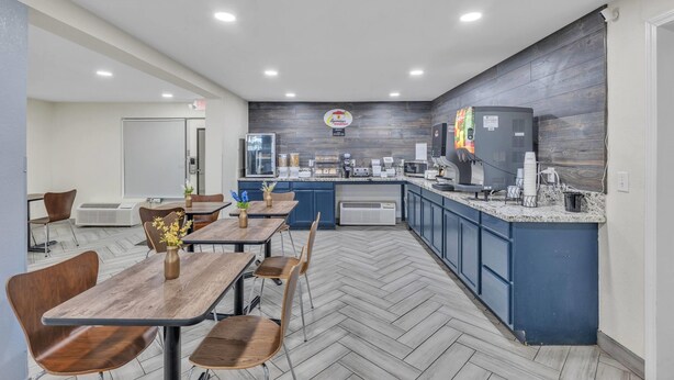 A modern kitchen area with a central island, built-in appliances, and a seating area with tables and chairs. - Super 8 by Wyndham Morganton (Morganton)