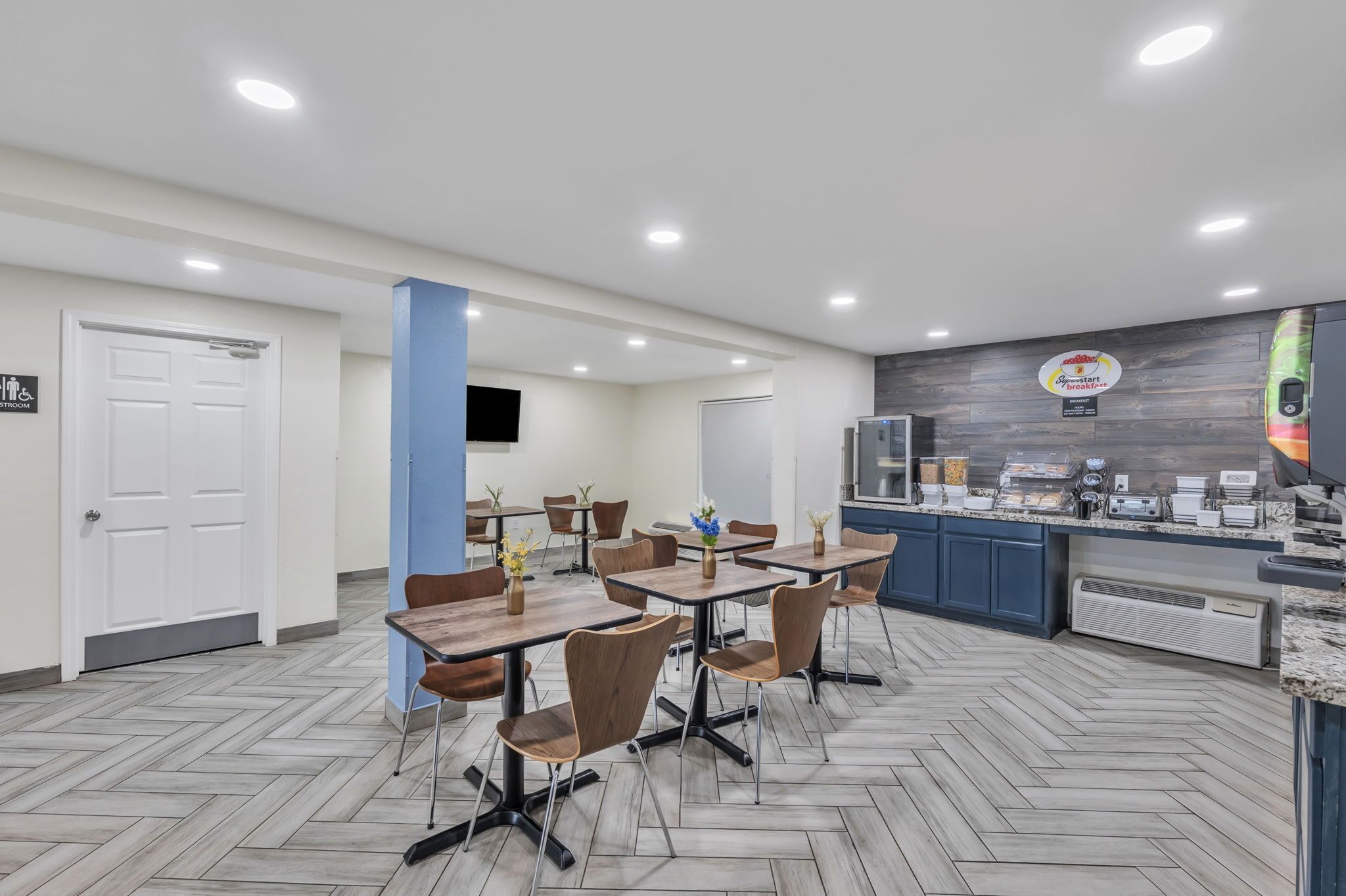 A modern kitchen area with a breakfast bar, a coffee machine, and a sign indicating a breakfast menu.