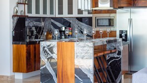 Une cuisine moderne dotée d’un îlot en marbre, de meubles en bois et d’un four à micro-ondes encastré.