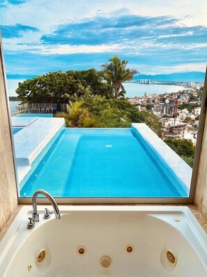 A view from a window of a swimming pool with a cityscape in the background. - Breathtaking View with open design and Game Room (Puerto Vallarta)