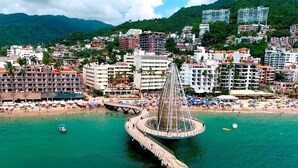 Un paysage urbain côtier avec un pont circulaire imposant, une plage et des immeubles résidentiels environnants.