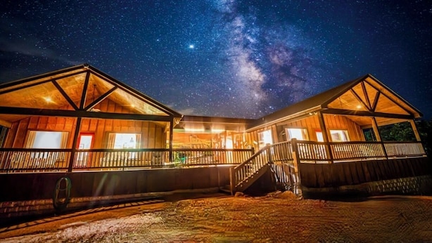 Una cabaña de madera con balcón, bajo un cielo estrellado.