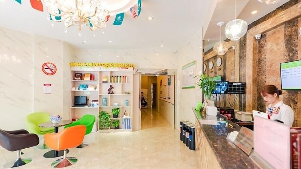 A hotel reception area with a reception desk, a chandelier, a TV, and a seating area with colorful chairs. - Greenhouse Hotel, Tongji Hospital, Guangxin Road, Shanghai (Shanghai)