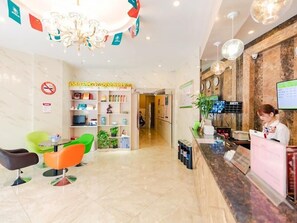 A hotel reception area with a reception desk, a chandelier, a TV, and a seating area with colorful chairs. - Greenhouse Hotel, Tongji Hospital, Guangxin Road, Shanghai (Shanghai)