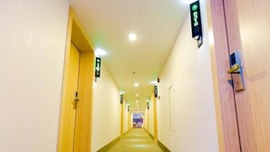 A hotel hallway with wooden doors, a carpeted floor, and directional signs. - Greenhouse Hotel, Tongji Hospital, Guangxin Road, Shanghai (Shanghai)