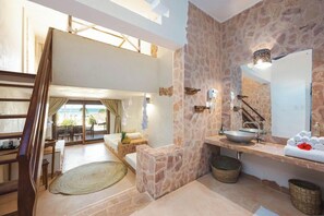 Un baño moderno con pared de piedra, un espejo grande, un lavamanos y un perchero para toallas.