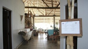 A restaurant with a thatched roof, wooden furniture, and a menu board. - Mvuvi Boutique Resort (Kiwengwa)