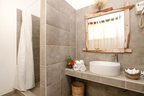 A bathroom with a white sink, a mirror with a wooden frame, and a shower curtain. - Mvuvi Boutique Resort (Kiwengwa)