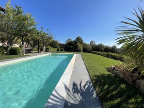 A swimming pool with a clear blue water, surrounded by a well-maintained lawn and trees. - Villa Sounio (ATTICA)