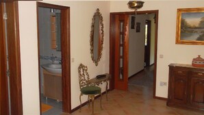 Un couloir avec un lavabo, un banc, un miroir et un placard.