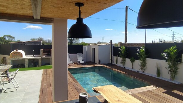 An outdoor pool area with a wooden deck, a barbecue grill, and a seating area with chairs and a table. - Villa with swimming pool located in a condominium near Béziers (Béziers)