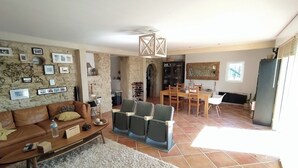 A living room with a brown sofa, a coffee table, and a rug. There is a dining area with a table and chairs. - Villa with swimming pool located in a condominium near Béziers (Béziers)