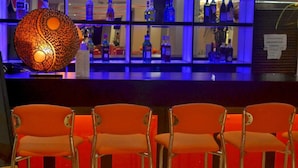 A bar area with orange chairs and a shelf of liquor bottles.