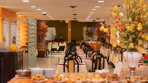 A dining area with tables set for a meal, chairs, and a buffet line.