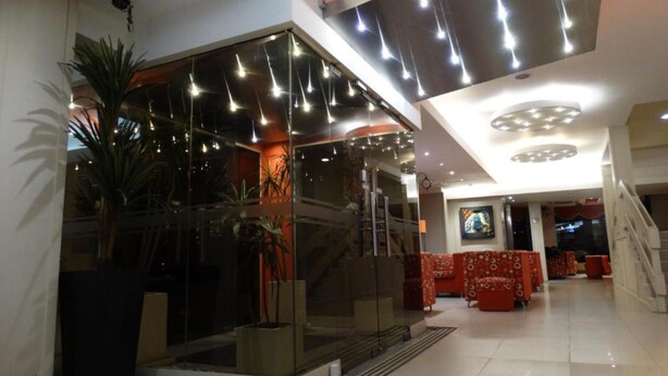 A modern lobby with a glass partition, a staircase, and red seating.