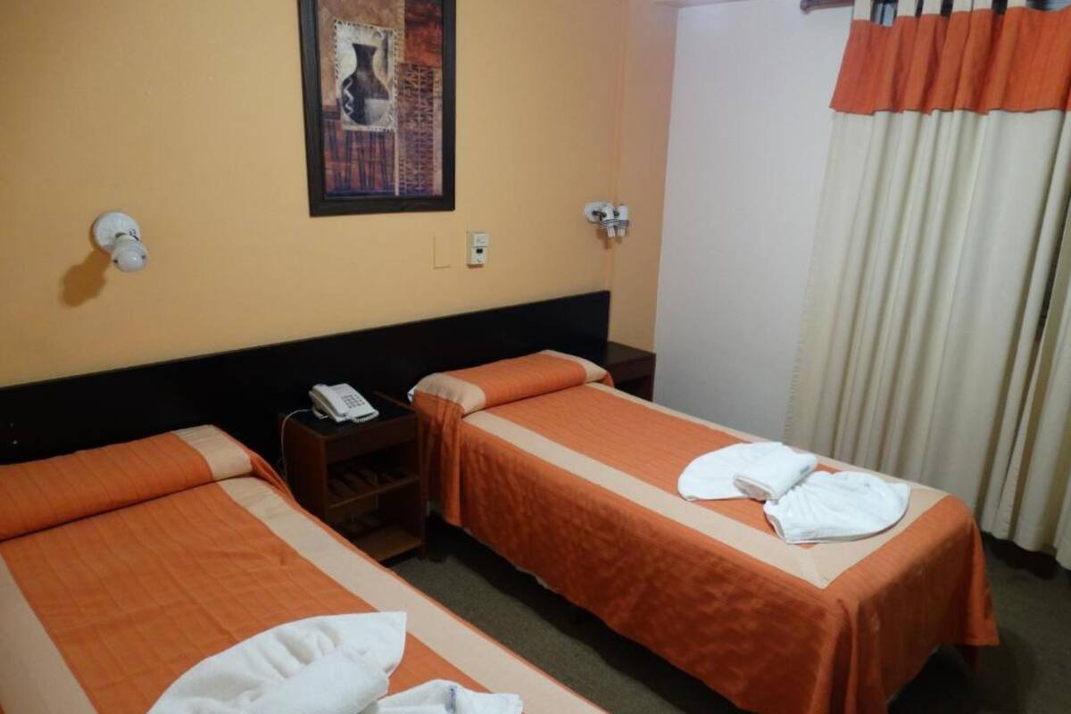 Quarto de hotel com duas camas, um telefone e um quadro na parede.