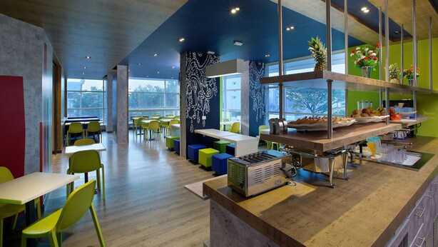 A modern cafeteria with high ceilings, large windows, and colorful seating. - Holiday Inn Express Pune Pimpri (Pune)