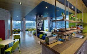 A modern cafeteria with high ceilings, large windows, and colorful seating. - Holiday Inn Express Pune Pimpri (Pune)