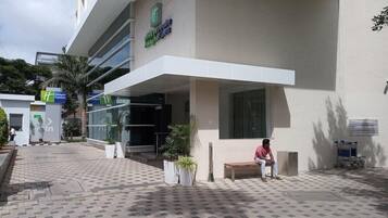 A modern building with a large entrance, a bench, and potted plants.