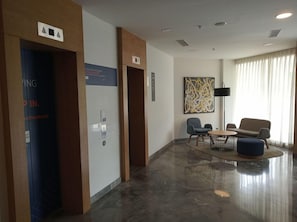 A hotel lobby with a reception desk, a seating area with a round table and chairs, a large abstract painting on the wall, and a large window with curtains. - Holiday Inn Express Pune Pimpri (Pune)