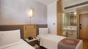 A hotel room with two beds, a bedside table with a phone, a wall-mounted lamp, and a bathroom with a sink and mirror. - Holiday Inn Express Pune Pimpri (Pune)