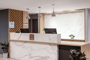 Taulell de recepció d'hotel amb superfície de marbre, un panell de paret de fusta i tres llums penjants.