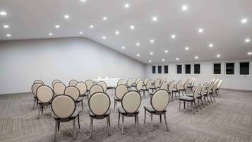 A large conference room with rows of chairs and tables, carpeted floor, and ceiling lights.