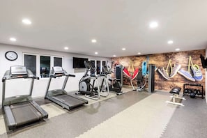 Una sala de gimnàstica amb cintes de córrer, el·líptiques i una bicicleta d'exercici penjada a la paret.