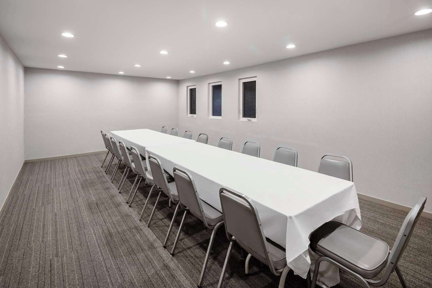 Una sala de conferencias con una larga mesa, sillas y piso alfombrado.