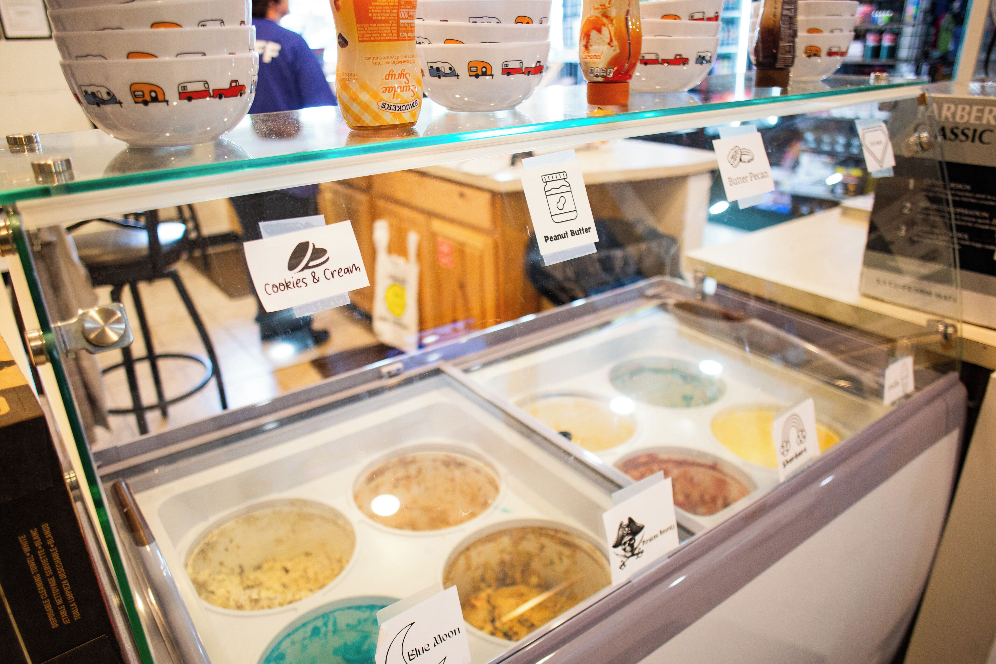 A dessert display case with various ice cream flavors labeled, including 'Cookies & Cream' and 'Blue Moon.'