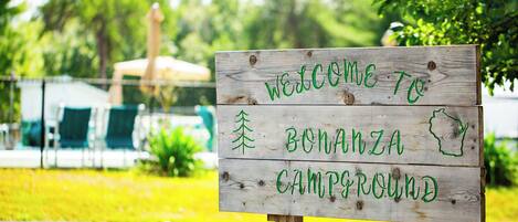 Uma placa de madeira com a inscrição 'WELCOME TO BONANZA CAMPGROUND'.