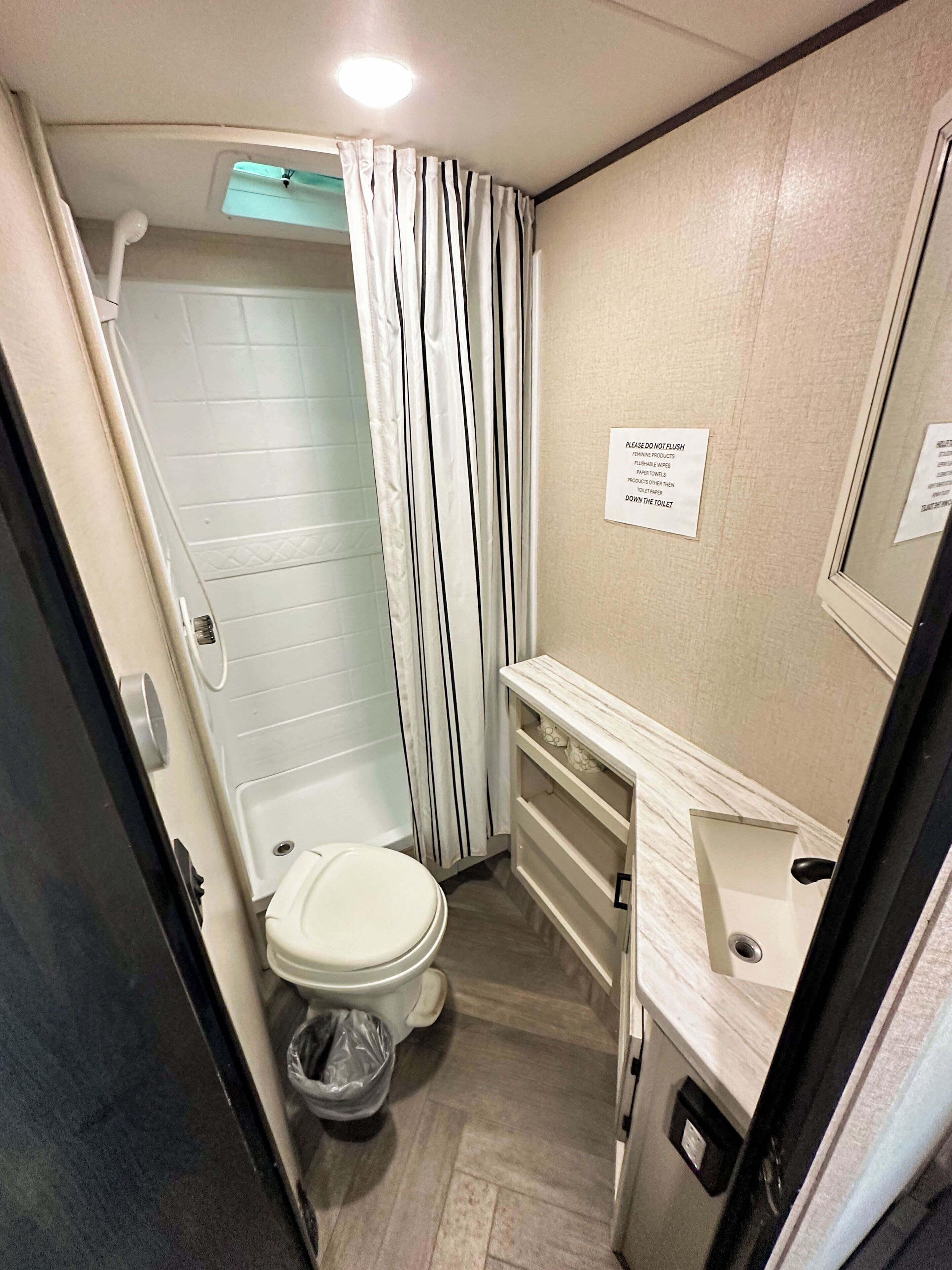 Ein kleines Badezimmer mit Toilette, Dusche und Waschtisch mit Spiegel.